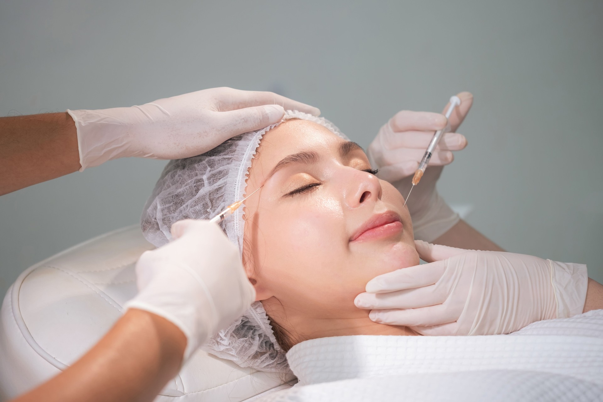 Medico che indossa il guanto e usa la siringa facendo iniezione alla bella donna. Chirurgia plastica in clinica. Cosmetologia e concetto di cura della pelle. Schiarere e levigare le rughe sulla pelle del viso